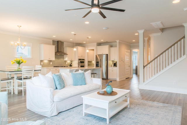 living room featuring ceiling fan, light wood-type flooring, ornamental molding, stairs, and recessed lighting