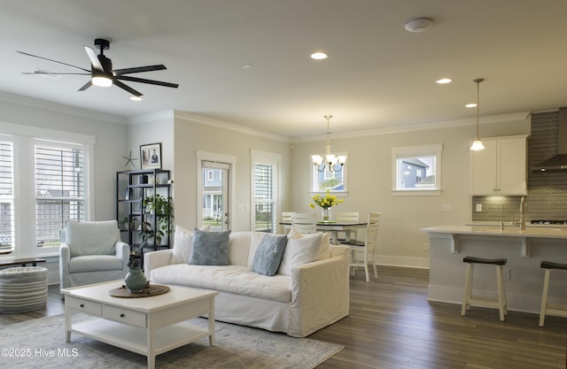 living area featuring ceiling fan, a chandelier, baseboards, dark wood finished floors, and ornamental molding