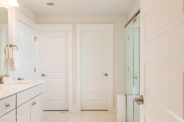 full bathroom with marble finish flooring, a shower with shower door, and vanity