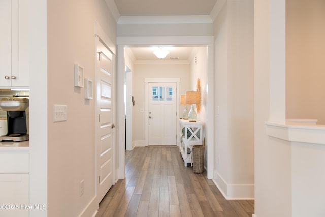 hallway featuring wood finished floors, ornamental molding, and baseboards