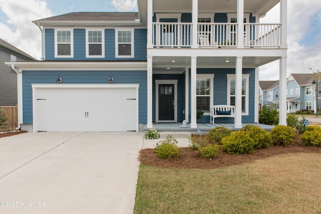 view of front facade featuring a porch, a balcony, a garage, concrete driveway, and a front lawn