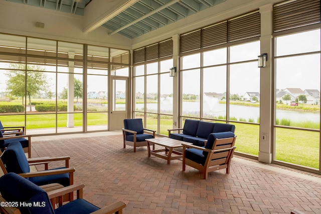 sunroom with a water view, an outdoor hangout area, and brick flooring