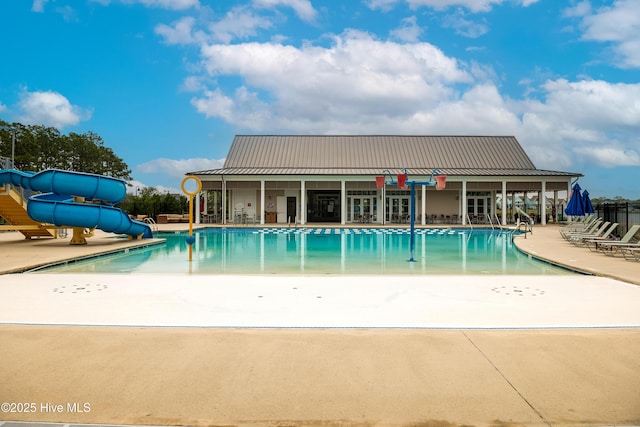 community pool with a water slide and a patio