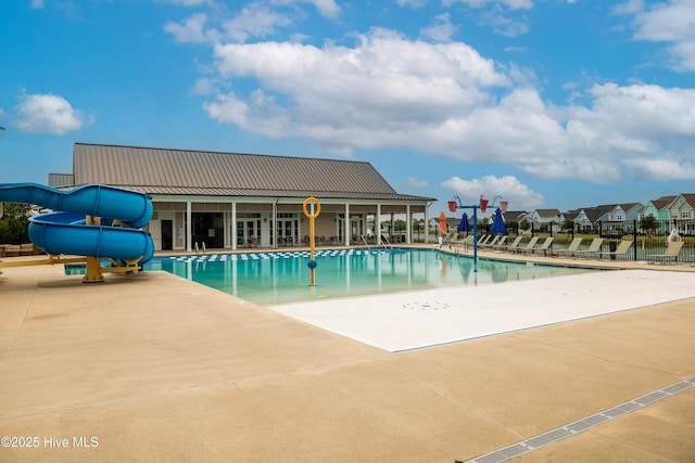 community pool featuring a water slide, fence, and a patio area