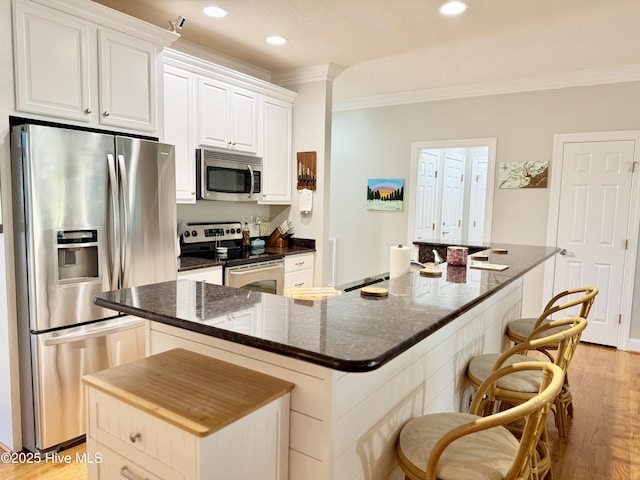 165 Laurel Oak Ln, Pinebluff, NC 28373 - kitchen with stainless steel appliances, crown molding, a spacious island, white cabinets, and light wood-type flooring
