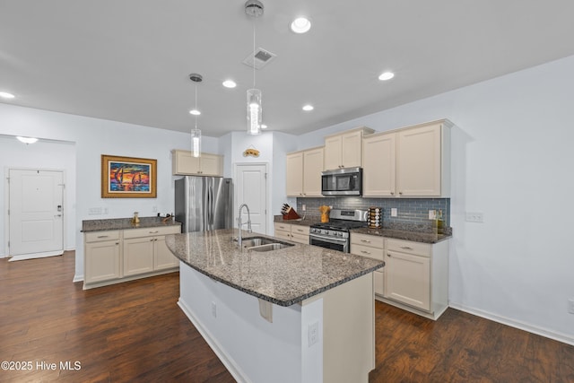 7351 Bellacroft Dr, Leland, NC 28451 - kitchen featuring stainless steel appliances, a sink, tasteful backsplash, a center island with sink, and dark wood-style flooring