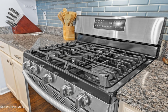 7351 Bellacroft Dr, Leland, NC 28451 - kitchen view of stainless steel range with gas stovetop, backsplash, dark wood-type flooring, and white cabinetry