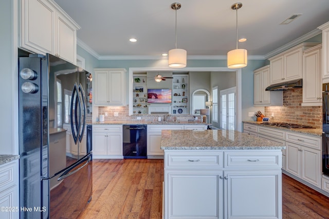 kitchen featuring visible vents, black appliances, under cabinet range hood, a sink, and backsplash