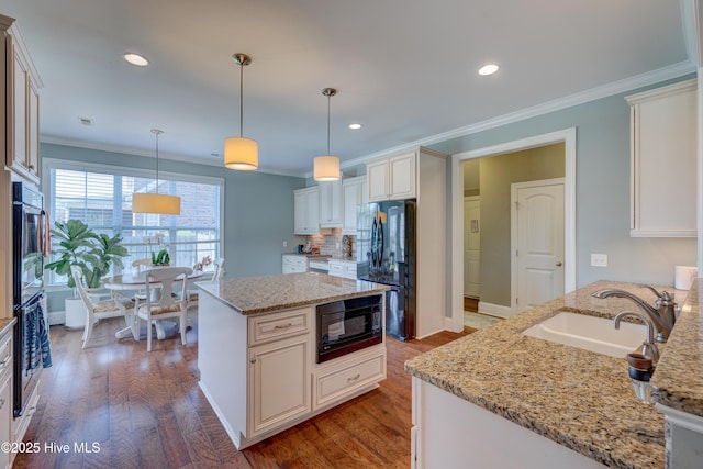 kitchen with a sink, ornamental molding, black appliances, wood finished floors, and light stone countertops