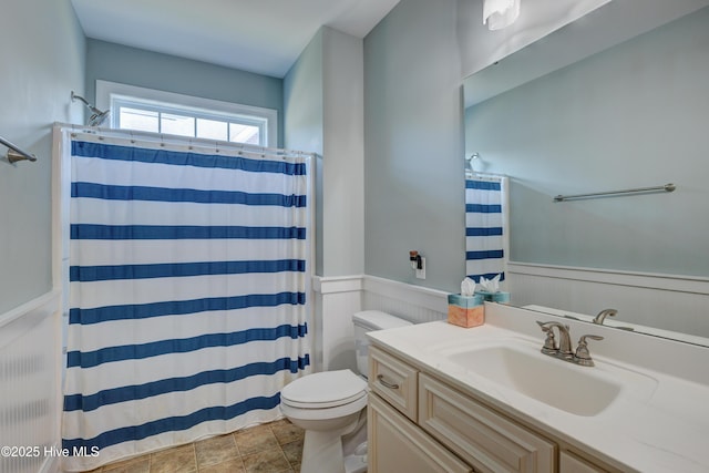 full bath featuring toilet, curtained shower, vanity, and a wainscoted wall