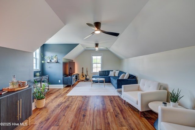 living area featuring wood finished floors, baseboards, a ceiling fan, and lofted ceiling