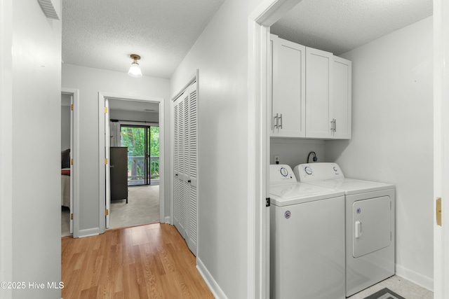 laundry room with cabinet space, separate washer and dryer, a textured ceiling, baseboards, and light wood-style flooring