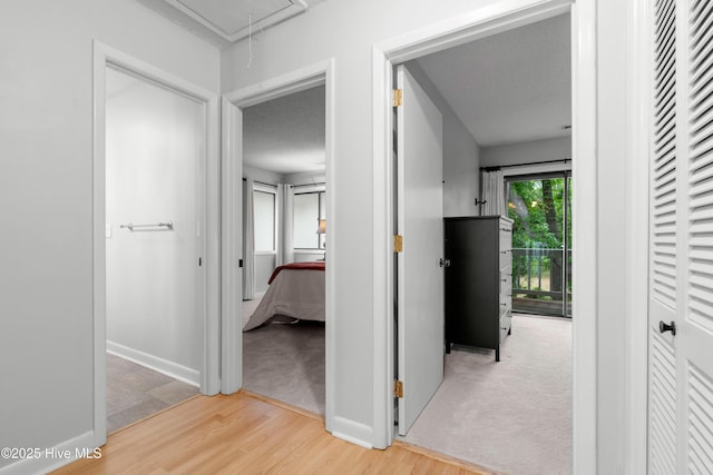 hallway with attic access, wood finished floors, baseboards, and carpet floors