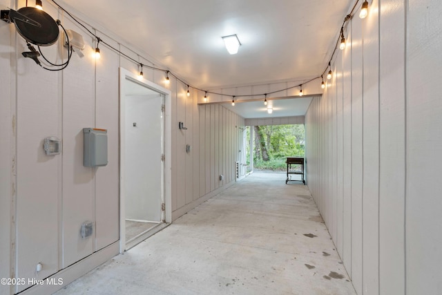 hallway with unfinished concrete floors and wooden walls