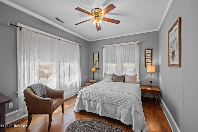 bedroom with crown molding, baseboards, visible vents, and wood finished floors