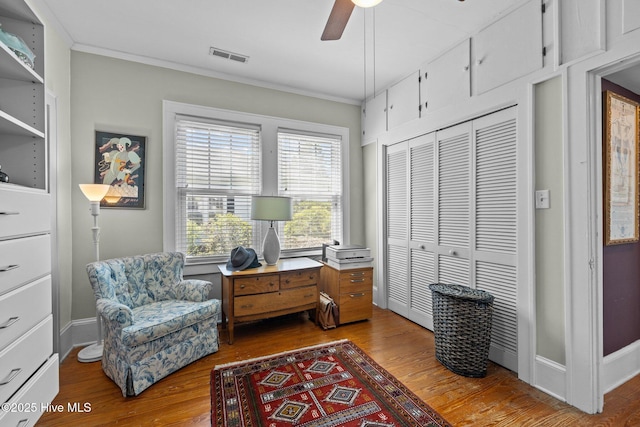 living area with visible vents, plenty of natural light, crown molding, and wood finished floors