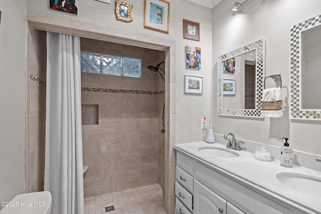 bathroom featuring double vanity, a sink, a tile shower, and toilet