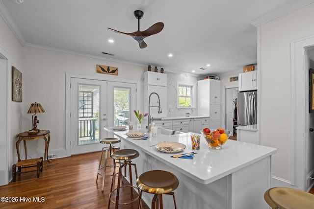 kitchen featuring crown molding, white cabinets, a breakfast bar, and dark wood-style floors