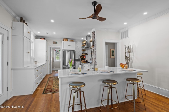 kitchen with freestanding refrigerator, a kitchen breakfast bar, and ornamental molding