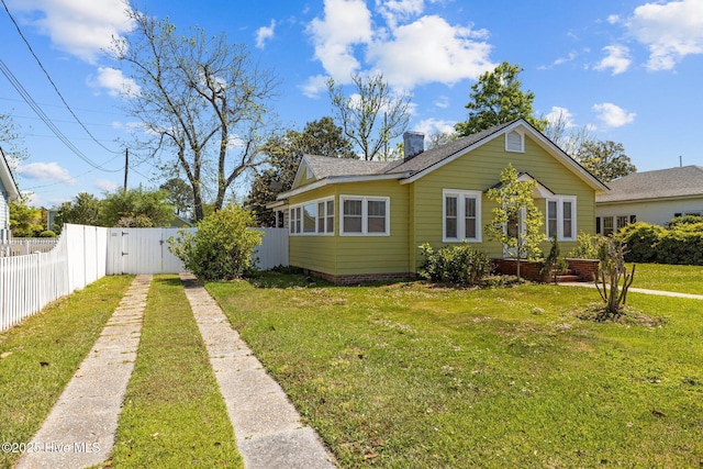 view of front of house with driveway, a chimney, a front yard, a gate, and fence