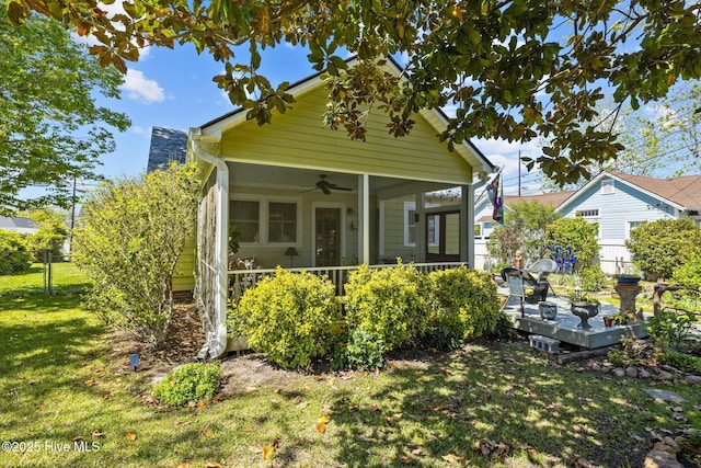 view of front facade with fence, a ceiling fan, a deck, and a front lawn