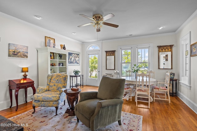 sitting room with baseboards, ornamental molding, a ceiling fan, and wood finished floors