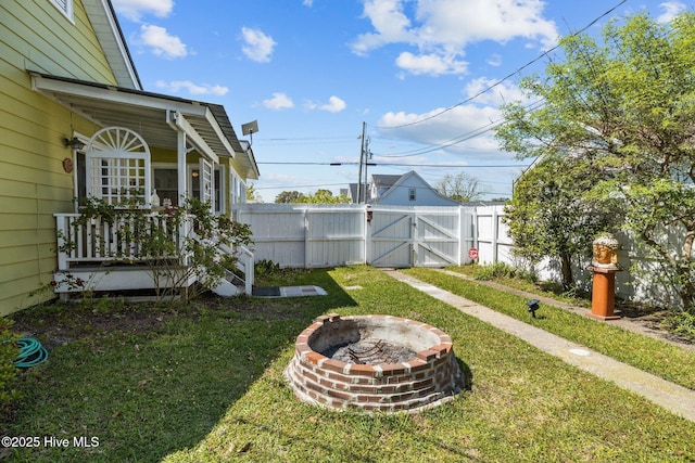 view of yard with fence, a gate, and an outdoor fire pit