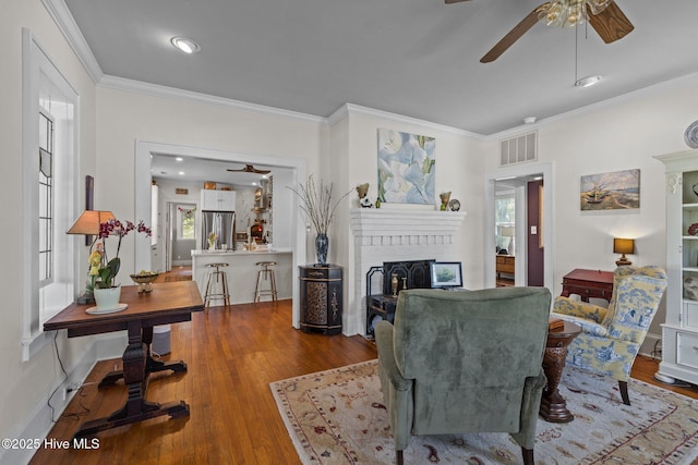 living room with visible vents, a ceiling fan, and crown molding