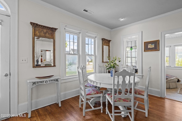 dining space featuring baseboards, ornamental molding, wood finished floors, and visible vents
