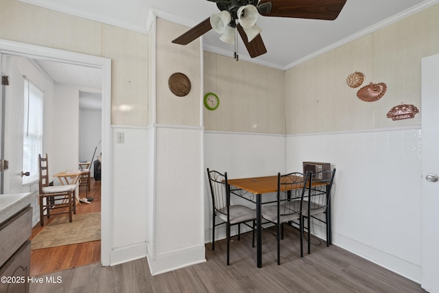 dining area featuring wainscoting, a ceiling fan, ornamental molding, and wood finished floors