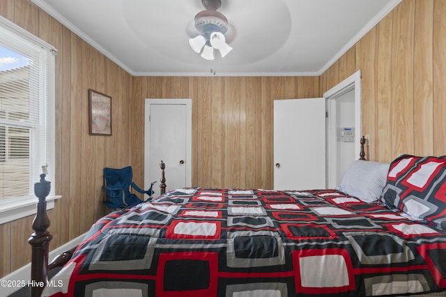bedroom featuring crown molding, wood walls, multiple windows, and a ceiling fan