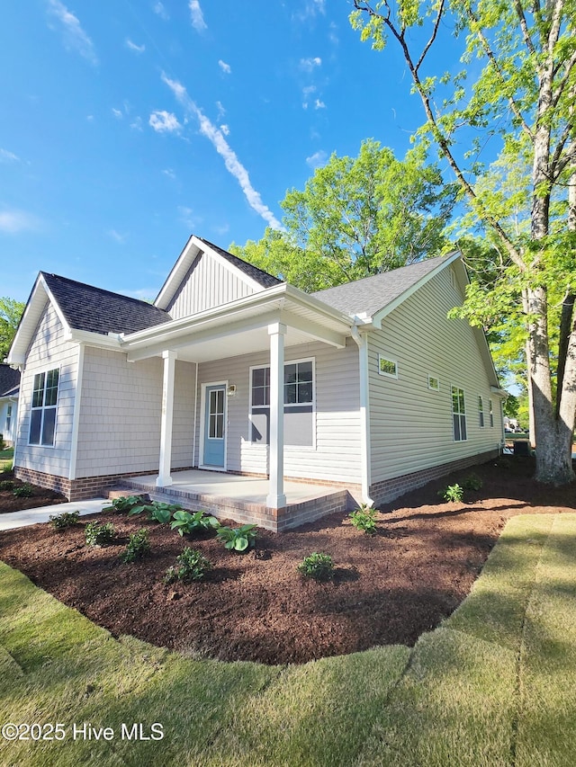 view of front of property featuring covered porch, board and batten siding, and roof with shingles
