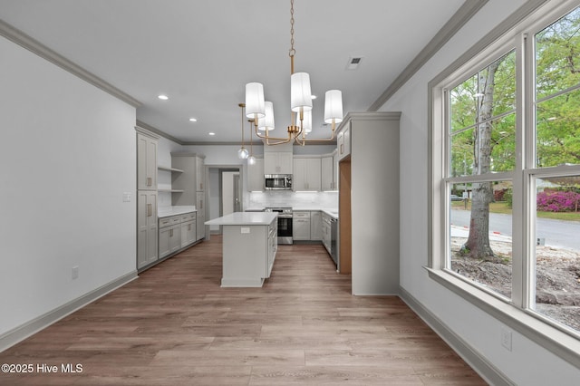 kitchen with open shelves, a chandelier, a center island, stainless steel appliances, and ornamental molding