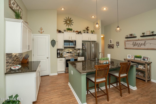 kitchen with stainless steel appliances, white cabinets, decorative backsplash, and lofted ceiling