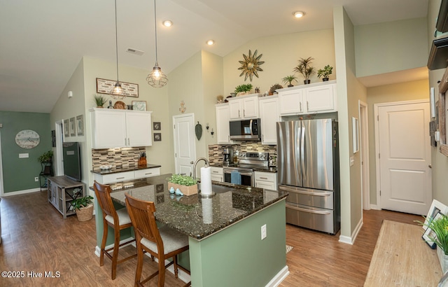 kitchen with high vaulted ceiling, tasteful backsplash, white cabinetry, visible vents, and stainless steel appliances
