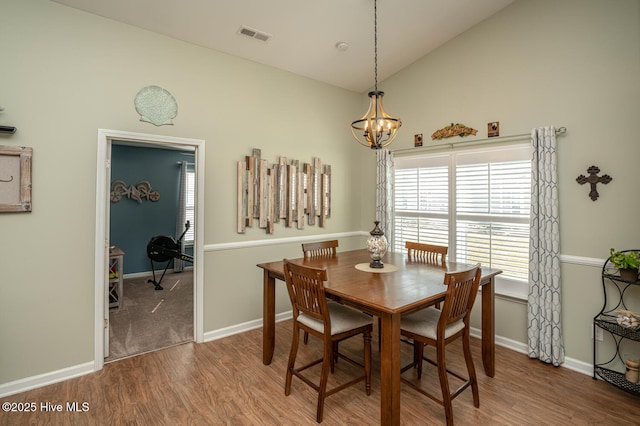 dining space featuring visible vents, high vaulted ceiling, an inviting chandelier, and wood finished floors