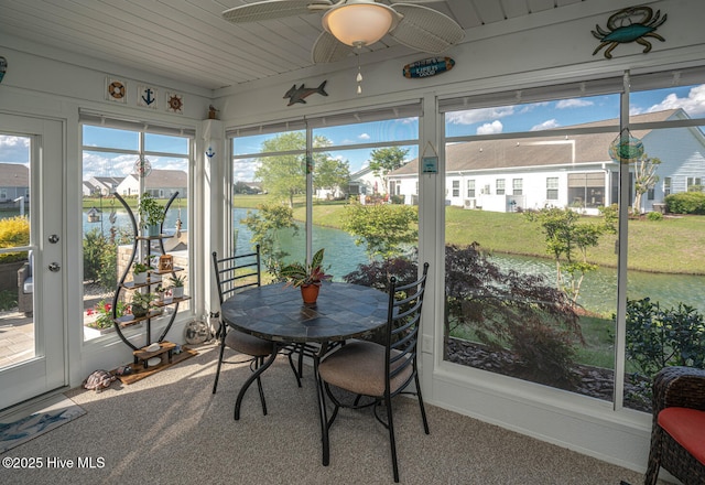 sunroom / solarium featuring a water view, ceiling fan, carpet flooring, and plenty of natural light