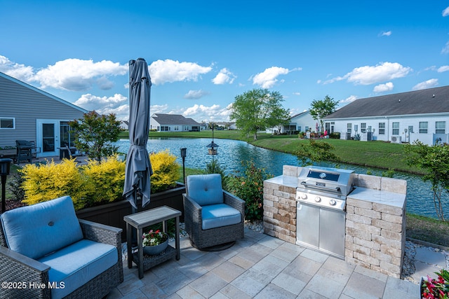 view of patio / terrace with a water view, exterior kitchen, a residential view, and a grill