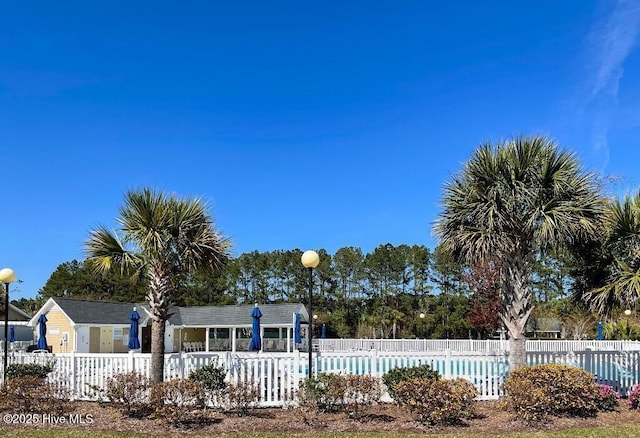view of front of home with a community pool and fence