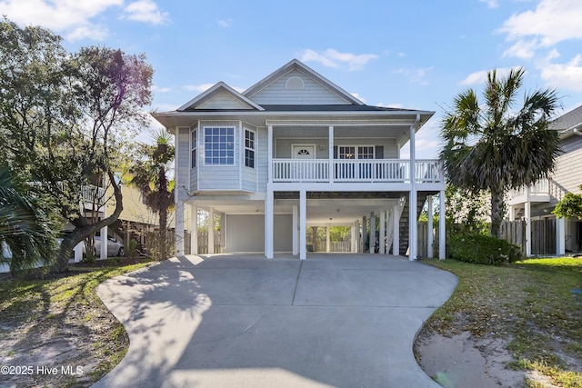 coastal inspired home featuring concrete driveway, a carport, a porch, and stairway