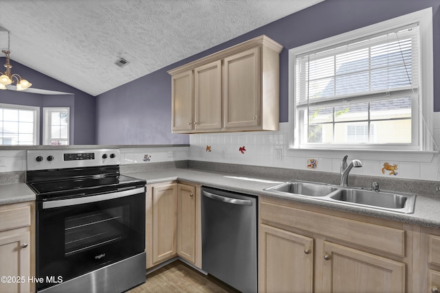 kitchen with light brown cabinetry, a textured ceiling, a sink, and stainless steel appliances
