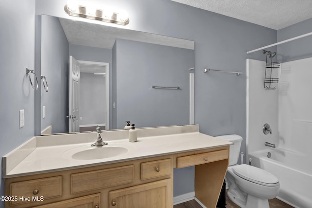 bathroom with toilet, a textured ceiling, vanity, and washtub / shower combination