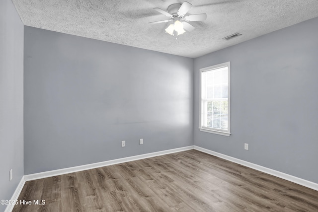spare room with visible vents, baseboards, a ceiling fan, a textured ceiling, and wood finished floors
