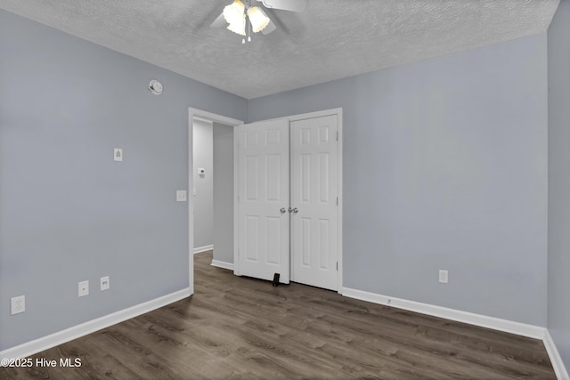 unfurnished bedroom featuring a closet, baseboards, wood finished floors, and a textured ceiling