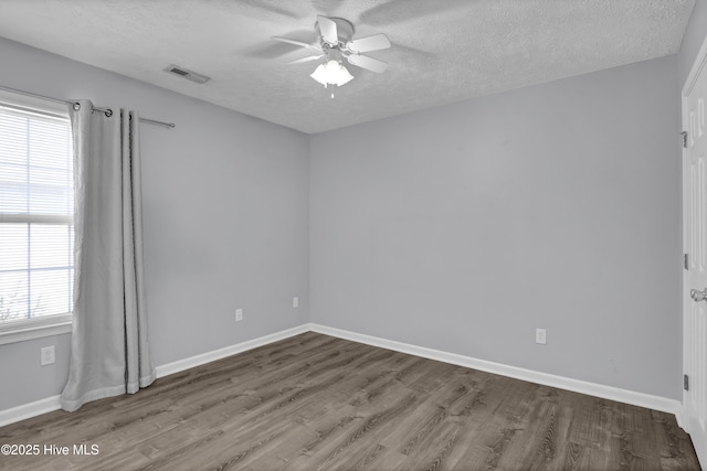 empty room with ceiling fan, wood finished floors, and a textured ceiling