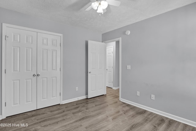 unfurnished bedroom featuring a closet, baseboards, wood finished floors, and a textured ceiling