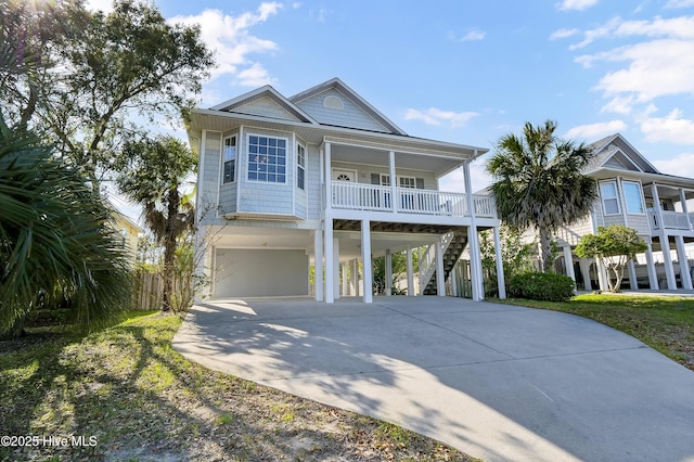 raised beach house featuring a carport, a porch, stairway, and concrete driveway