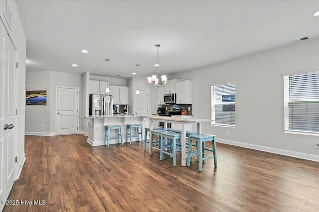 kitchen with baseboards, a spacious island, dark wood finished floors, an inviting chandelier, and stainless steel appliances