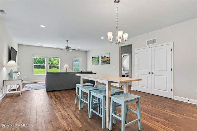 dining space featuring visible vents, baseboards, ceiling fan with notable chandelier, and dark wood-type flooring