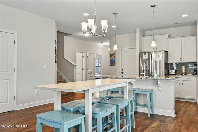 kitchen featuring light stone countertops, white cabinetry, a chandelier, stainless steel refrigerator with ice dispenser, and dark wood-style floors